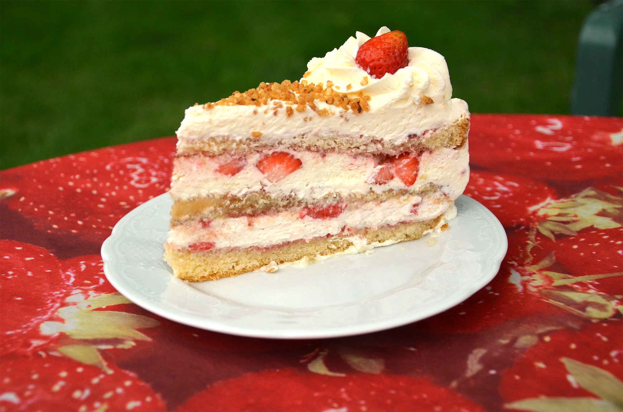 Das Bild zeigt einen Teller mit einem Stück Sahnetorte mit Erdbeeren 