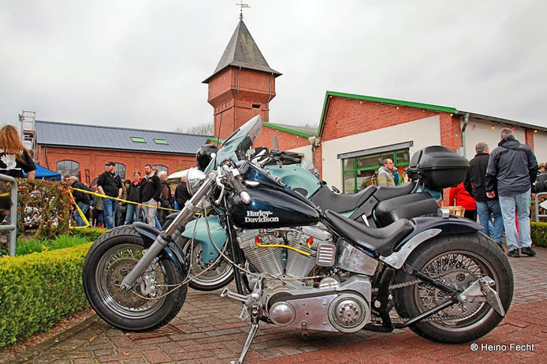 Das Bild zeigt ein Motorrad, im Hintergrund sieht man den Eisenhüttenturm in Augustfehn.