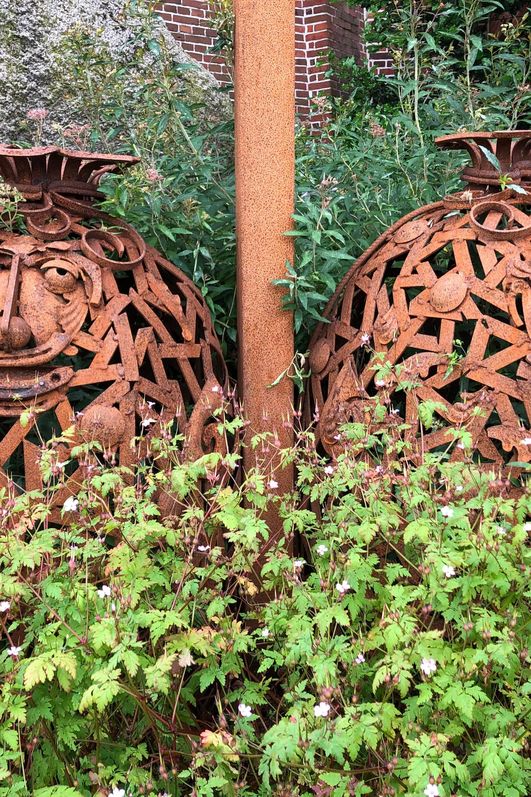 Zwei Mehlsäcke aus Eisen stehen vor einer historischen Mühle