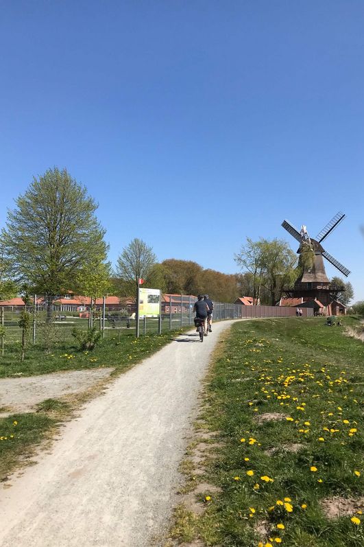 Das Foto zeigt einen Radweg mit zwei Radfahrern ,im Hintergrund ist die Hengstforder-Mühle zu sehen.
