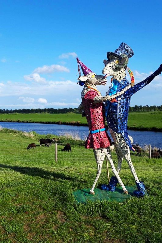 2 bunte Schafe aus Eisen tanzen am Deich