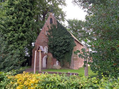 Alte Backsteinkapelle mit Grünbewuchs und altem Baumbestand