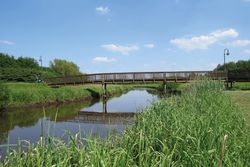 Eine schmale Holzbrücke überspannt einen Fluss